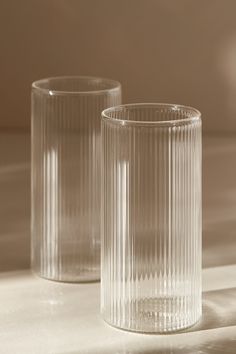 two clear glass vases sitting on top of a white countertop next to each other