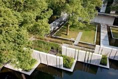 an aerial view of a park with benches and trees in the foreground, surrounded by water