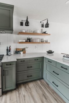 a kitchen with gray cabinets and white counter tops, wood flooring and open shelving