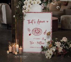 there is a sign with flowers and candles on the table