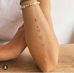 a woman's arm with tattoos on it sitting on top of a wooden table