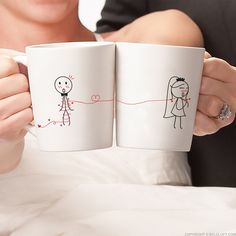 two people holding coffee mugs in their hands with drawings on the inside of them