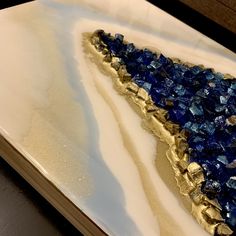 a blue and gold piece of art sitting on top of a white countertop next to a wooden table