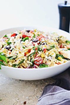 a white bowl filled with rice and veggies on top of a table next to a fork