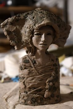 a clay sculpture of a woman wearing a hat