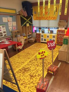 the inside of a classroom with yellow and red rugs on the floor next to wooden crates