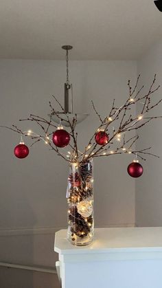 a vase filled with ornaments and lights on top of a white counter next to a wall