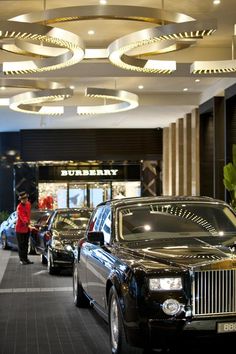 a car showroom filled with cars and people walking through the building's lobby