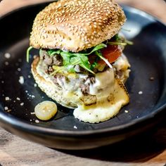 a hamburger with lettuce, tomato and other toppings on a black plate