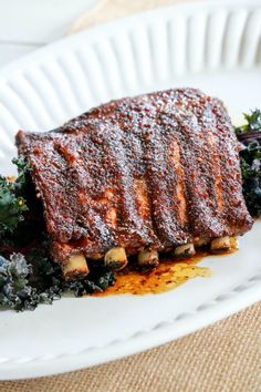 a piece of meat and greens on a white plate