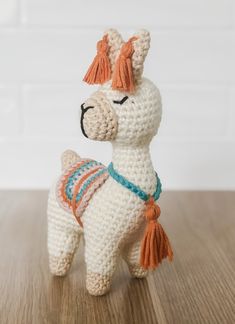 a crocheted white llama with orange tassels