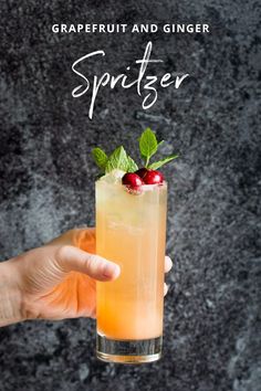 a hand holding a glass filled with a drink and garnished with cranberries