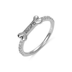 a white gold ring with a dog bone and diamonds on the side, in front of a