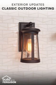 a wall mounted light on the side of a white brick wall with a candle in it