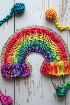 a rainbow made out of yarn on top of a wooden board