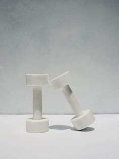 two white objects sitting on top of each other in front of a gray wall and floor