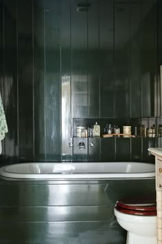 an old fashioned bathtub and toilet in a bathroom with dark wood paneling on the walls