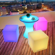 three different colored stools sitting on top of a wooden floor next to a table