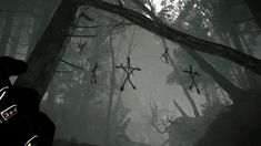 the video game is playing in the dark and foggy forest with crosses hanging from trees