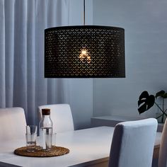 a dining room table with white chairs and a black lamp hanging from the ceiling