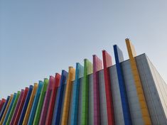 a tall multicolored building against a blue sky with no clouds in sight, it appears to be an art installation