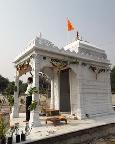 a man standing in front of a white building with an orange flag on the roof