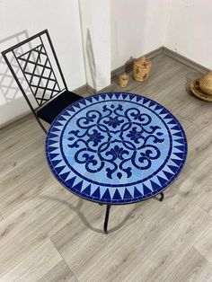 a blue and white table sitting on top of a wooden floor next to a chair