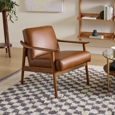 a brown leather chair sitting on top of a rug next to a table with a book shelf