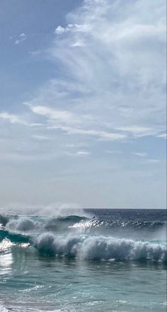 two surfers are riding the waves on their surfboards in the ocean under a cloudy blue sky