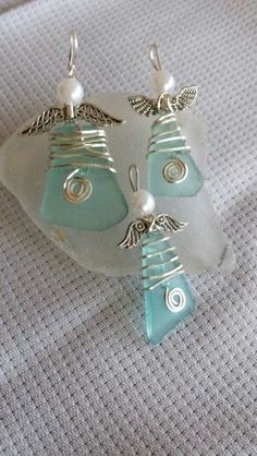 a pair of earrings sitting on top of a piece of glass next to a bead