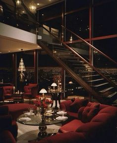 a living room filled with red couches next to a stair case in front of a window