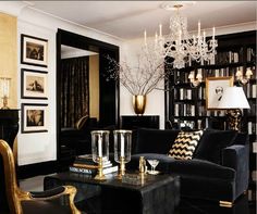 a living room filled with black furniture and a chandelier hanging from the ceiling