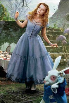 a woman in a blue dress standing next to a rabbit