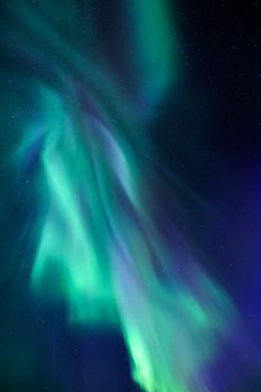 an aurora bore is seen in the night sky with green and blue lights above it