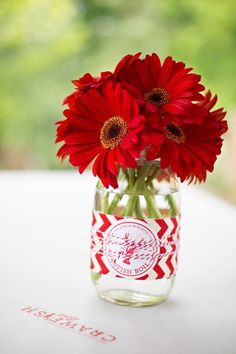 red flowers in a mason jar sitting on a table