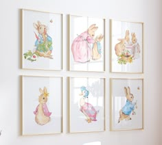 four framed pictures hang on the wall above a desk in a room with white walls