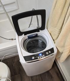 a washing machine with the door open in a bathroom