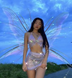 a woman in a silver outfit standing on the side of a road next to grass