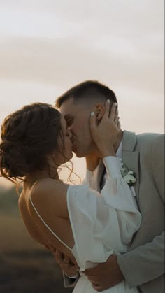 a bride and groom kissing in the sunset