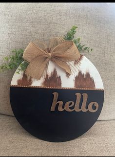 a black and white sign that says hello with a brown bow on it's front