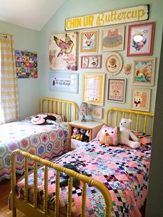 two beds in a room with pictures on the wall above them and an open window