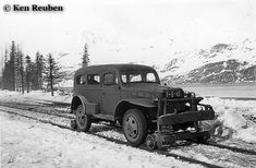 an old black and white photo of a truck on the side of a snowy road