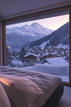 a large bed sitting in front of a window next to a snow covered mountain range