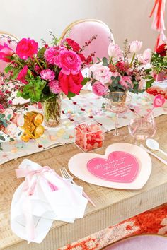 the table is set with pink and white flowers in vases, napkins, and plates