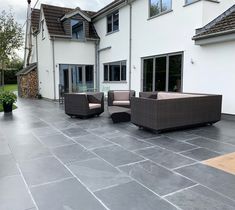 an outdoor patio area with furniture and potted plants on the side of the house