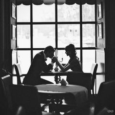 black and white photograph of two people sitting at a table in front of a window