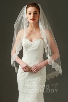 a woman in a wedding dress with a veil on her head and hands behind her back