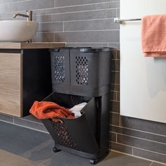 a black trash can sitting next to a bathroom sink