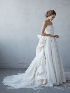 a woman in a white wedding dress standing against a wall