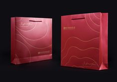 two red shopping bags on a black background, one is pink and the other is gold